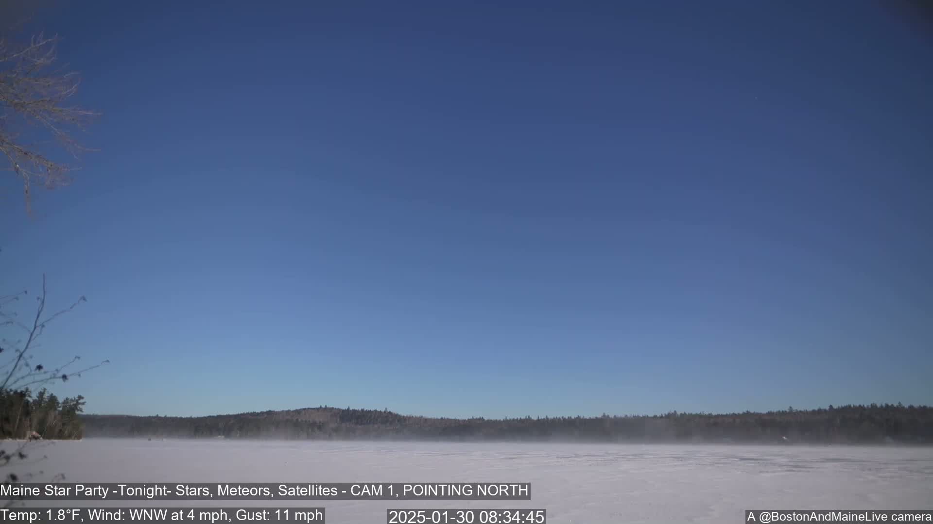 A frozen lake with a thin layer of fog is visible under a clear blue sky.