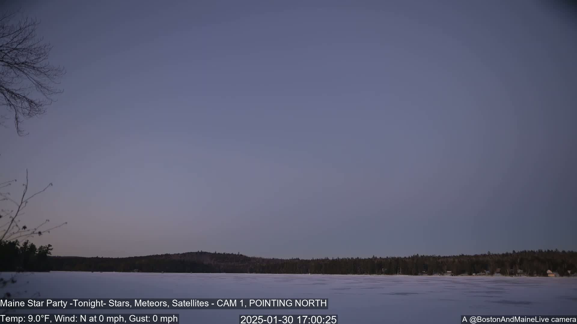 A calm, twilight sky over a frozen lake and distant, snow-covered trees.