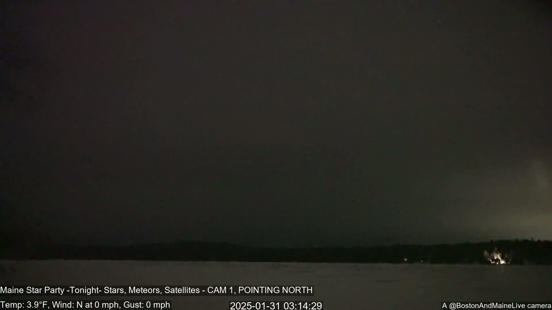 A nighttime, snow-covered landscape is visible under a dark sky with a few visible stars.
