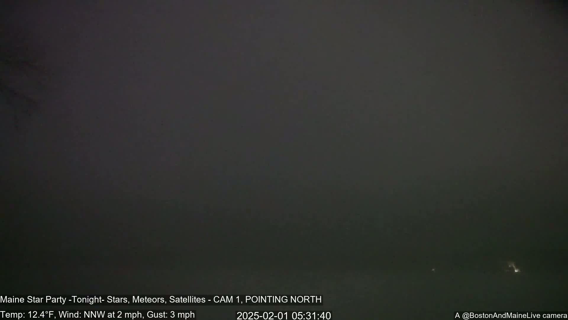 A dark, nighttime scene shows a hazy or foggy sky with a north-pointing camera showing a temperature of 12.4°F and a north-northwest wind of 2 mph with gusts up to 3 mph.