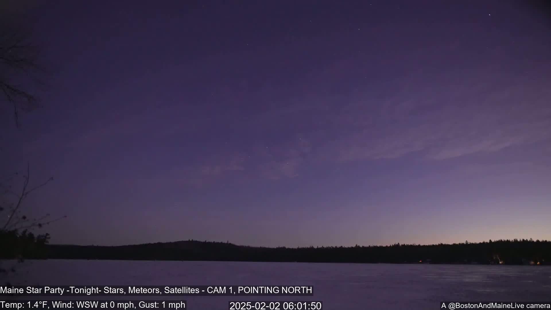 A dark purple twilight sky over a frozen lake and dark tree line, under calm, near-still conditions.
