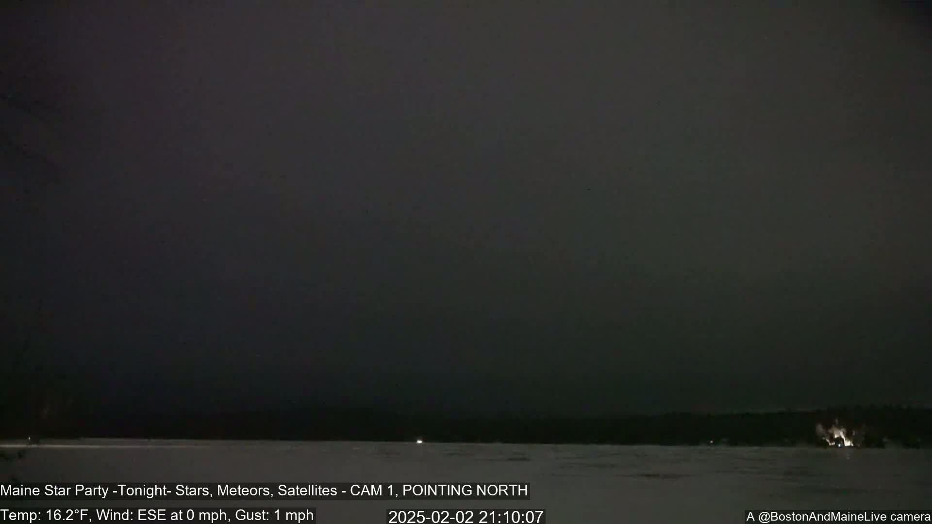 A dark, nighttime scene shows a snowy, flat landscape under a mostly clear, dark sky.