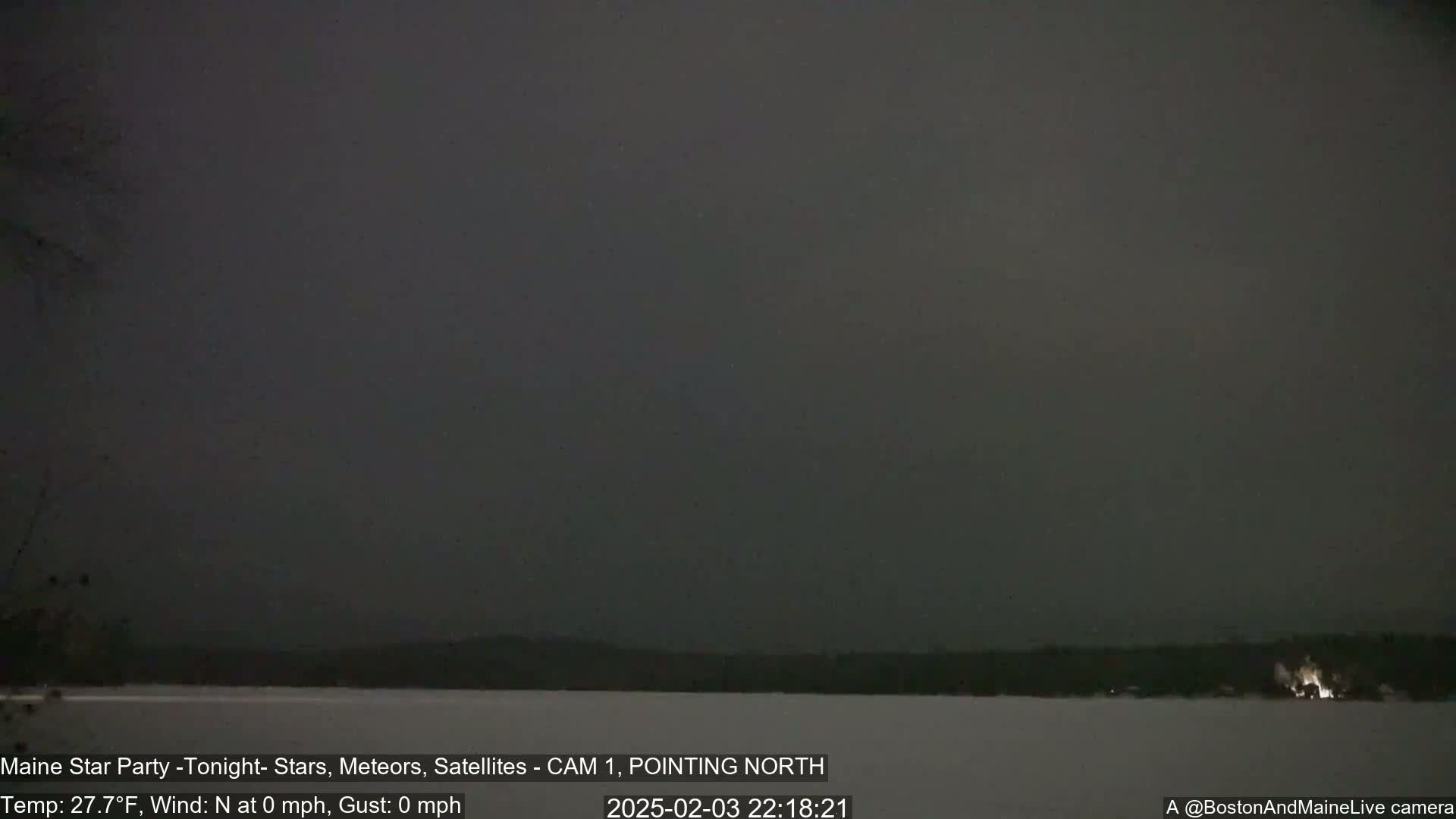 A nighttime, snow-covered landscape is visible under a dark, overcast sky with no wind.