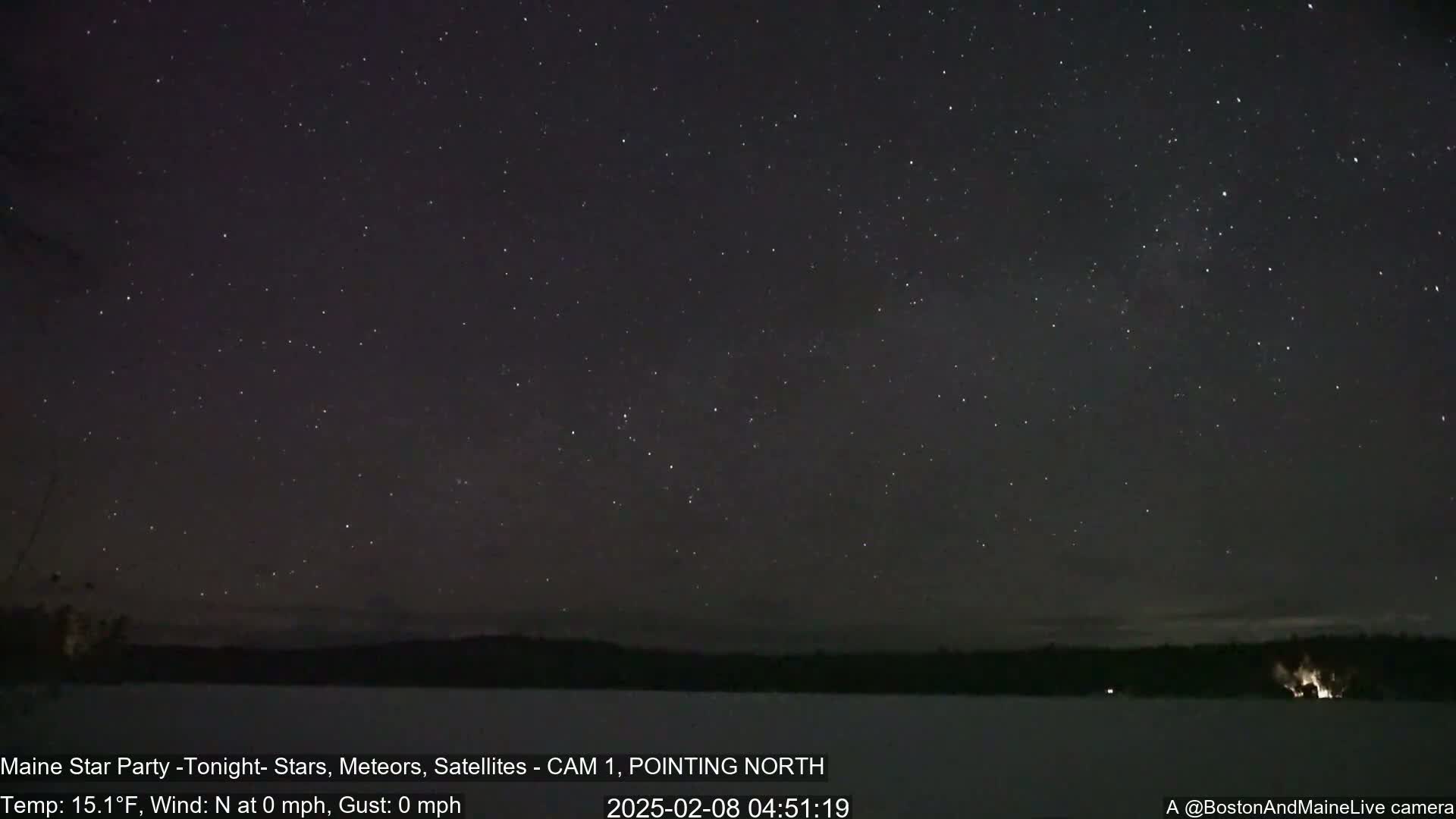 A nighttime long shot shows a dark sky filled with stars over a snow-covered landscape, with calm, cold weather conditions.