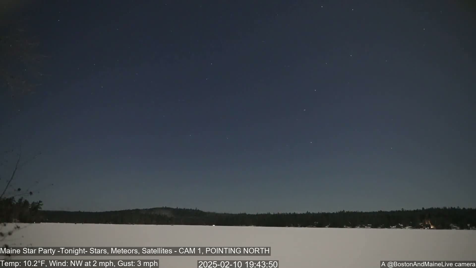 A snow-covered landscape is visible under a dark, clear night sky dotted with stars.