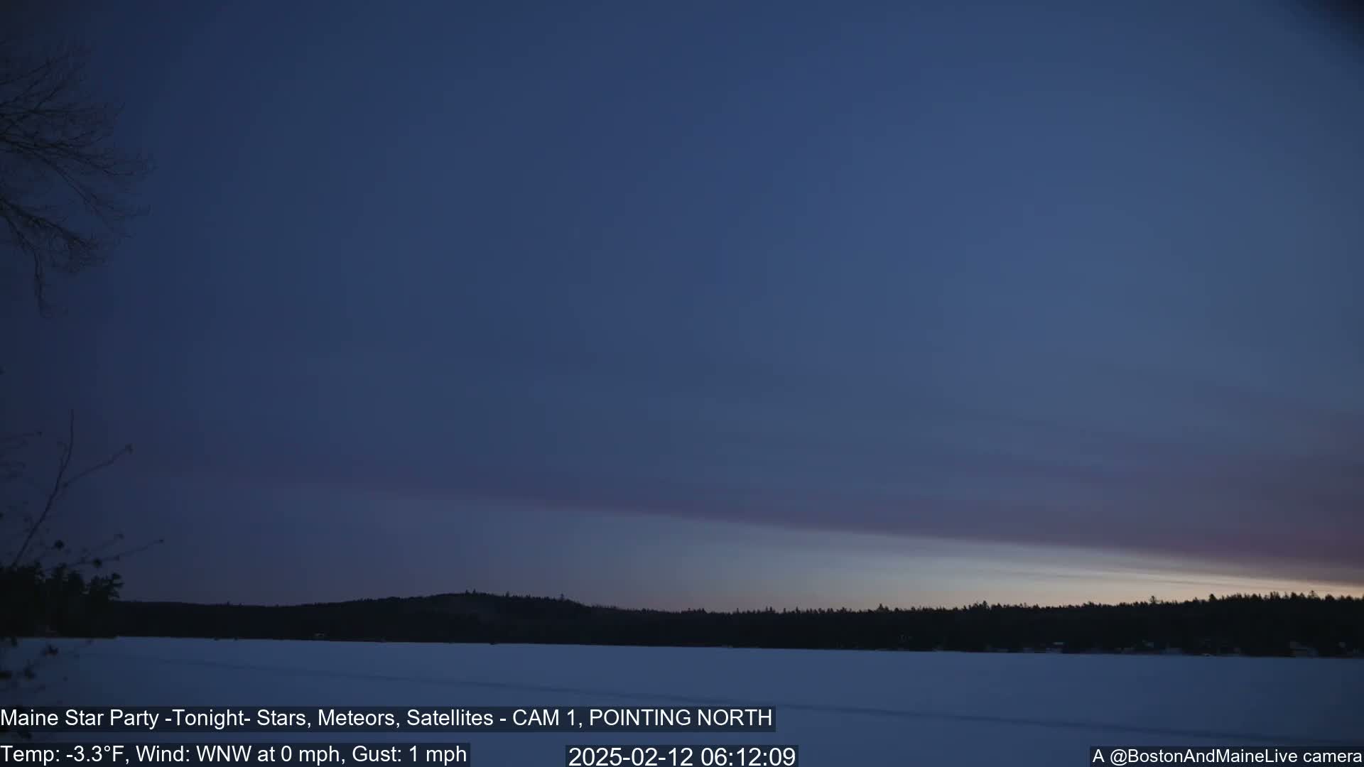 A frozen lake is visible under a twilight sky, with a dark treeline in the background.