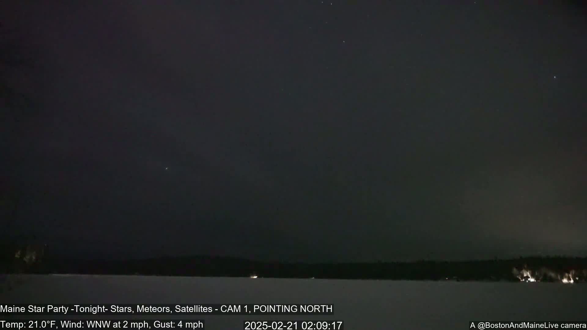 A nighttime, snowy landscape is visible under a dark sky speckled with stars, with a light wind blowing.