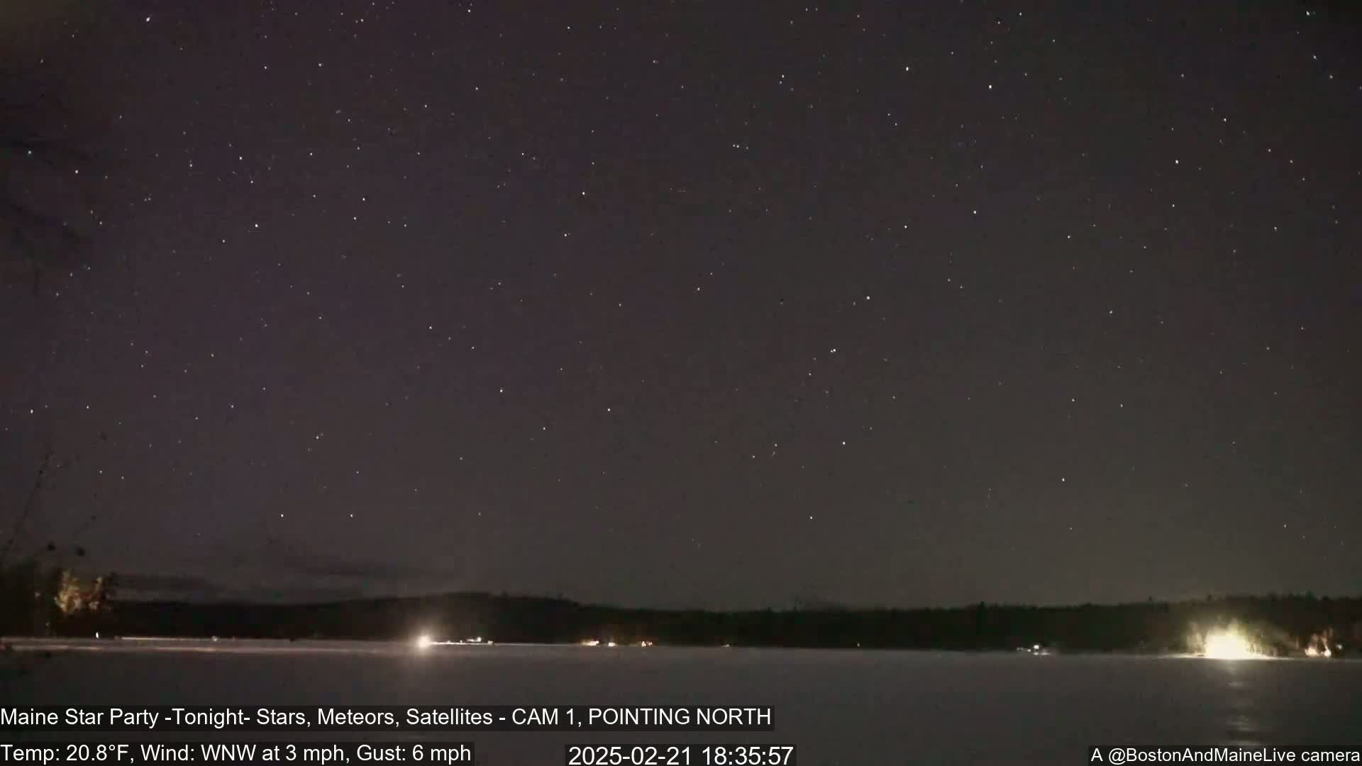A clear, cold night sky filled with stars is visible over a frozen lake and dark treeline.