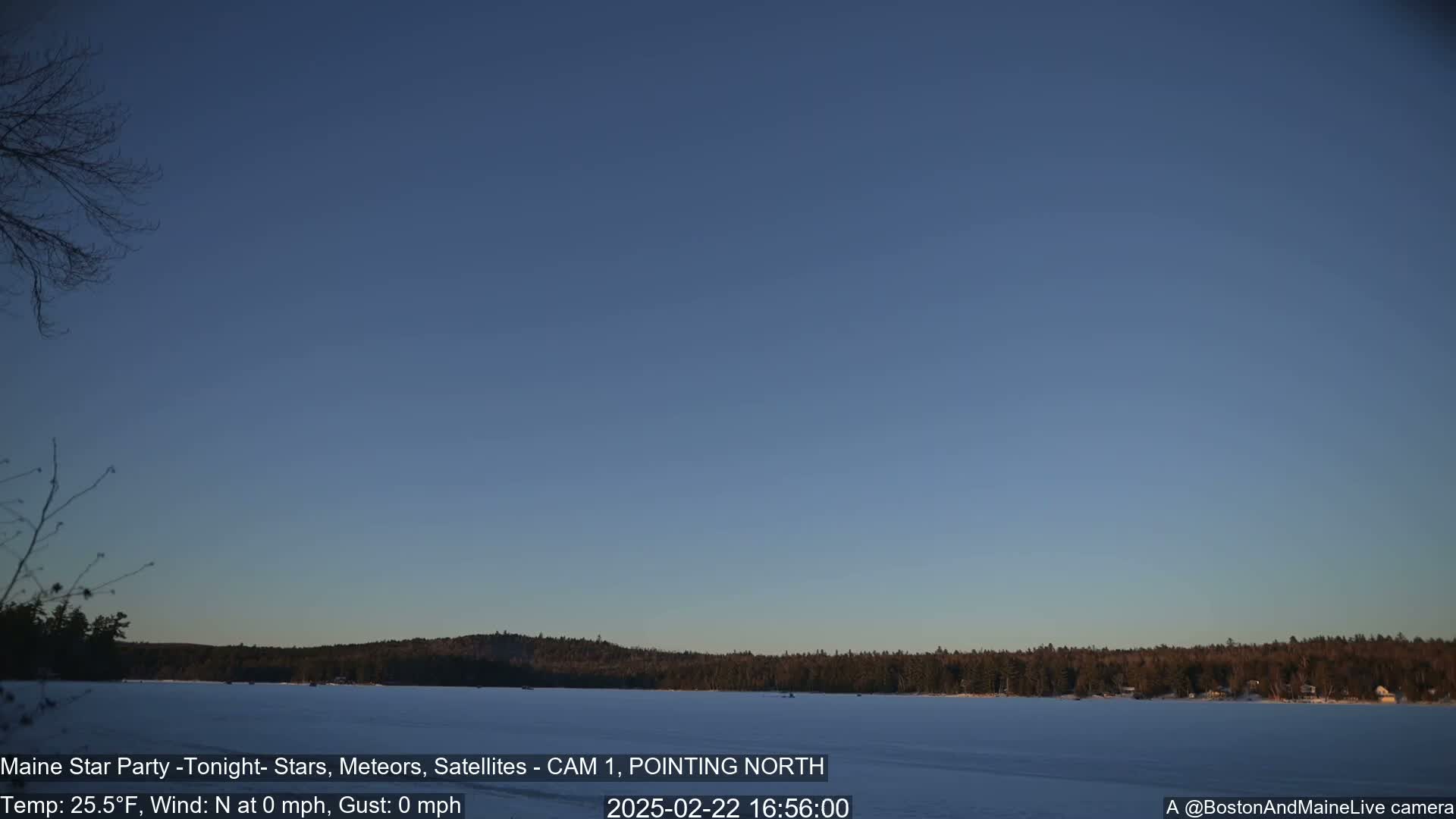 A frozen lake is visible under a clear, twilight sky, with a dark tree line in the distance.
