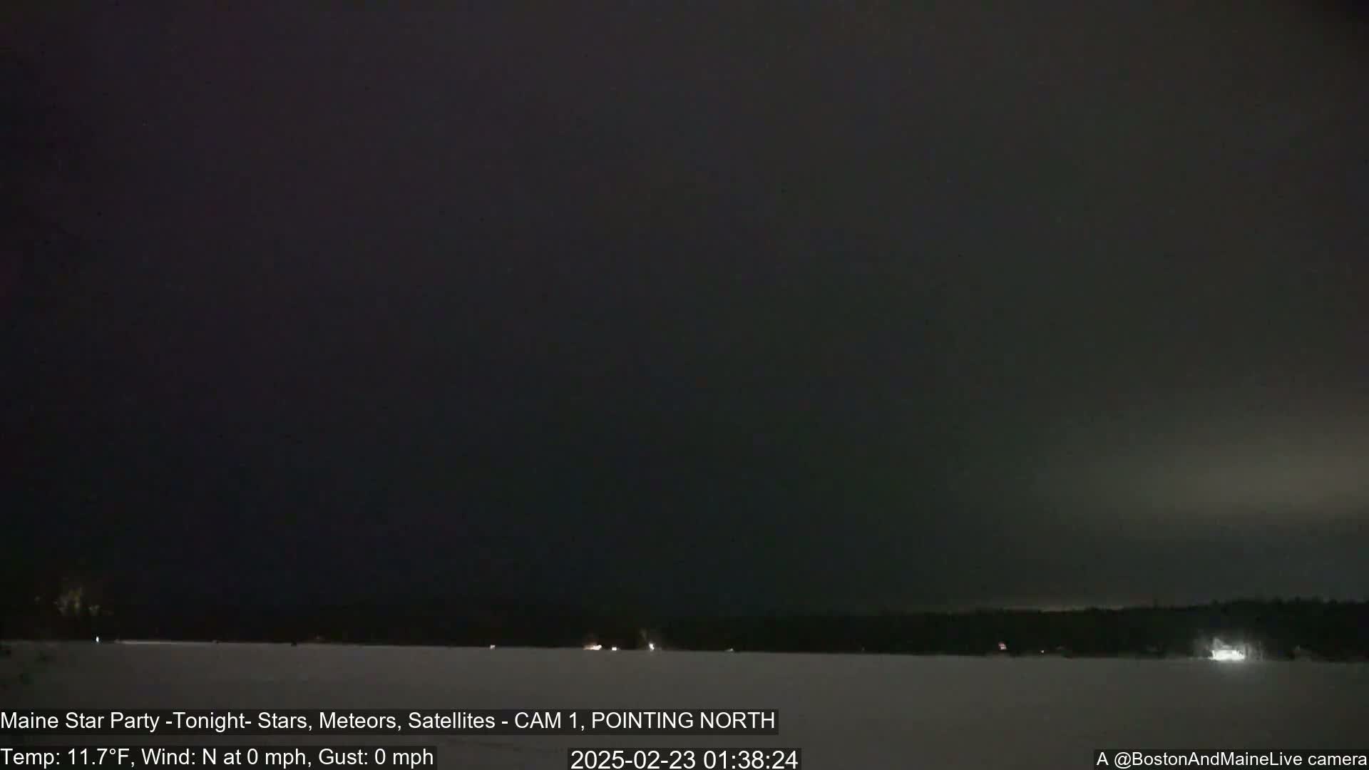 A nighttime, snow-covered landscape is visible under a dark sky with calm, clear conditions.