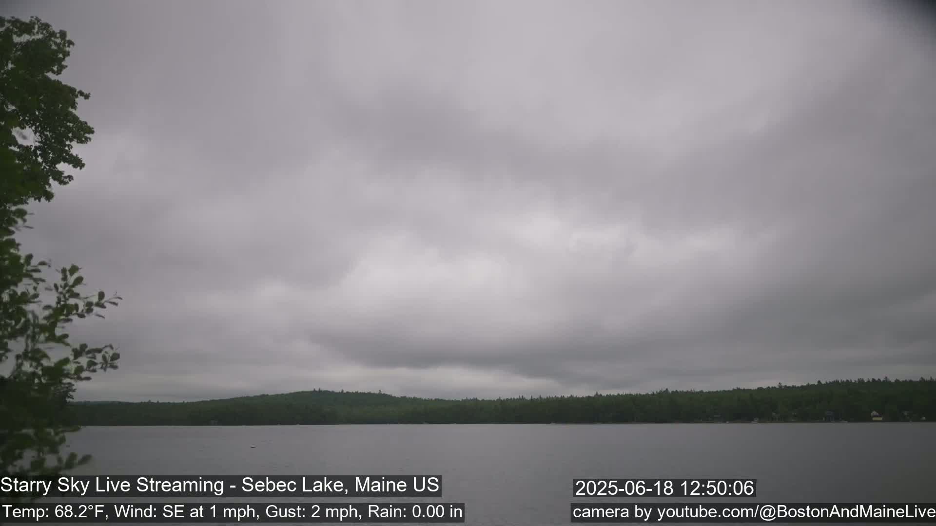 A calm lake is seen under an overcast sky, with a slight wind.