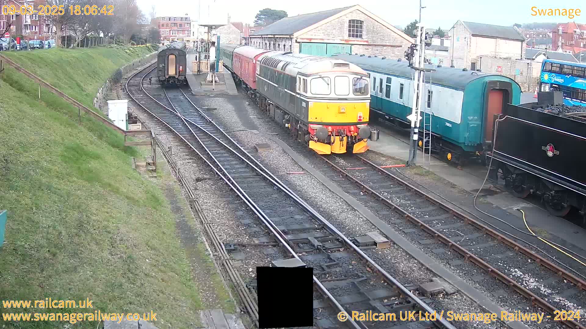 Several railway carriages and locomotives are parked on train tracks in an overcast outdoor setting.