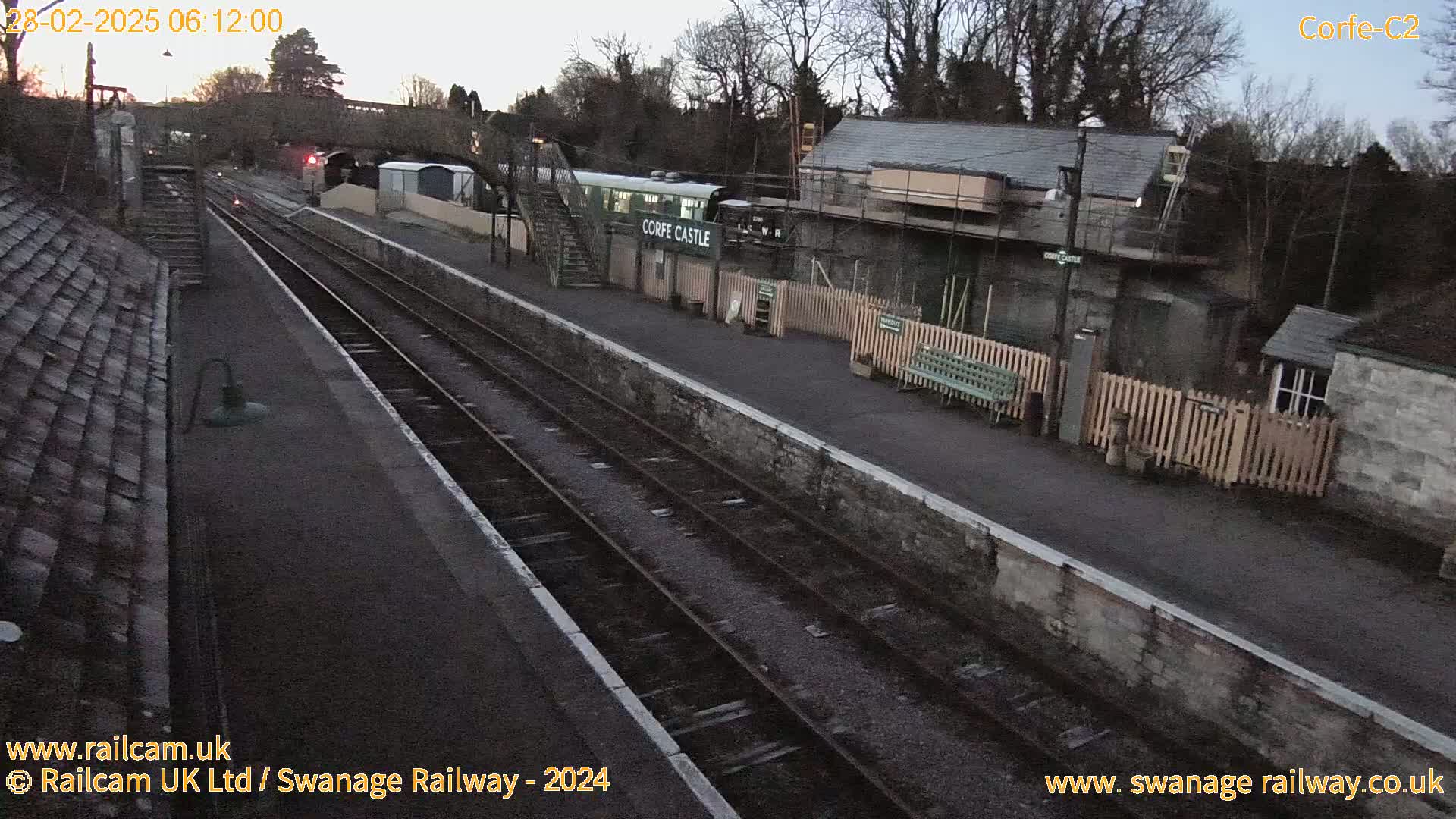 A train sits at a railway station platform under a dusky sky.