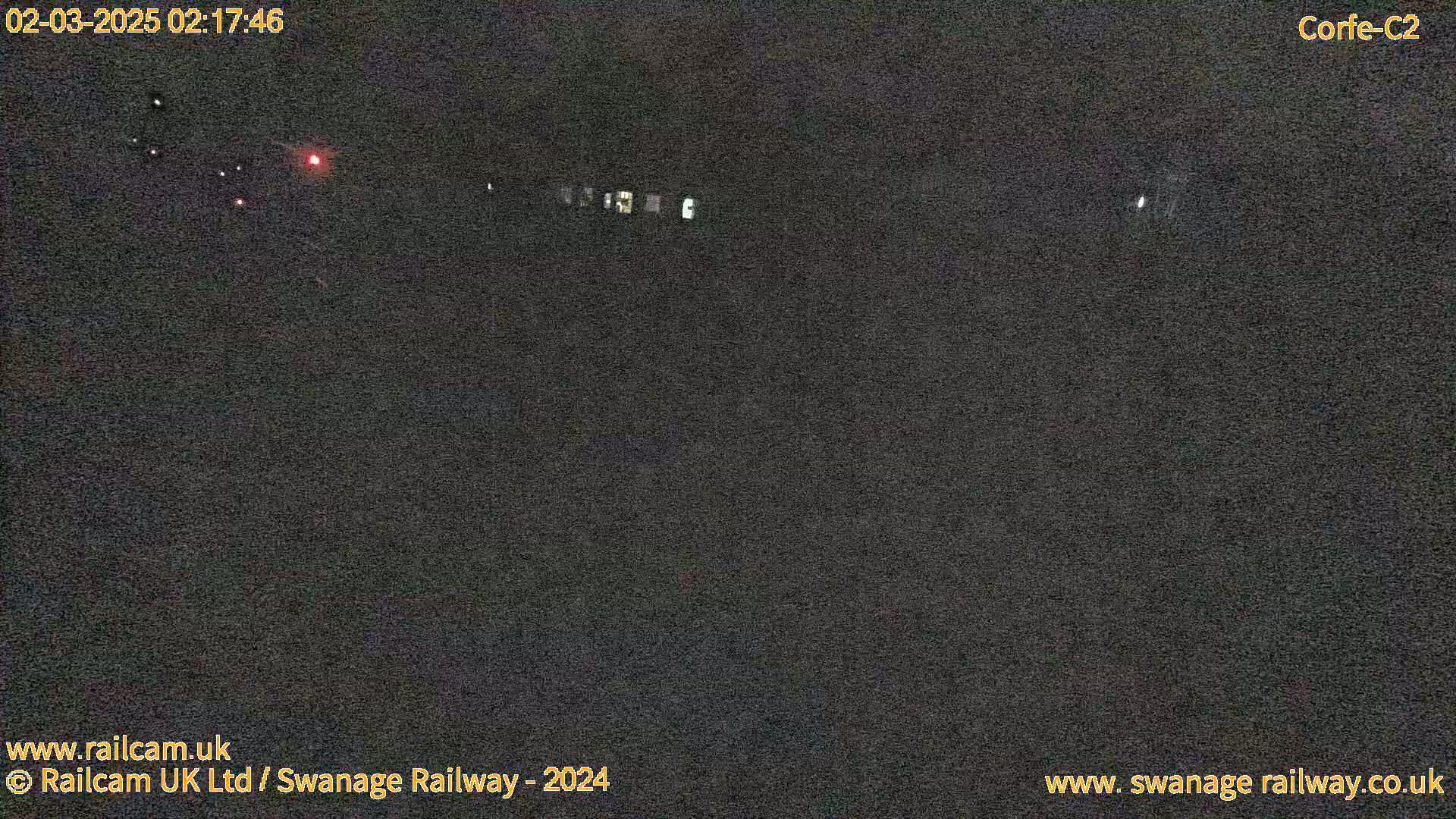 A dark, nighttime scene shows a few faint lights in the distance.