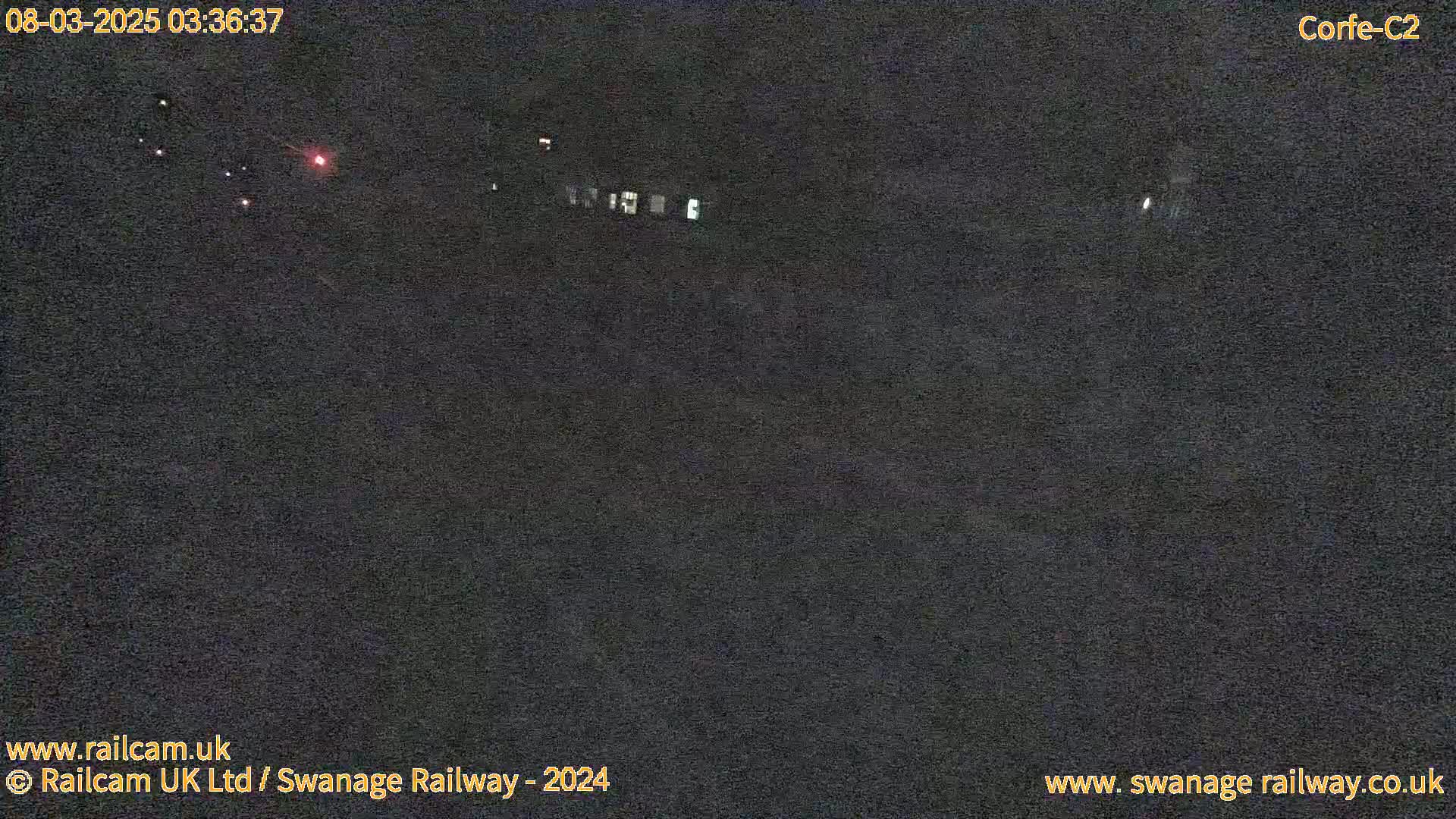 A nighttime, low-light view of a dark, seemingly empty area with a few faint, distant lights.