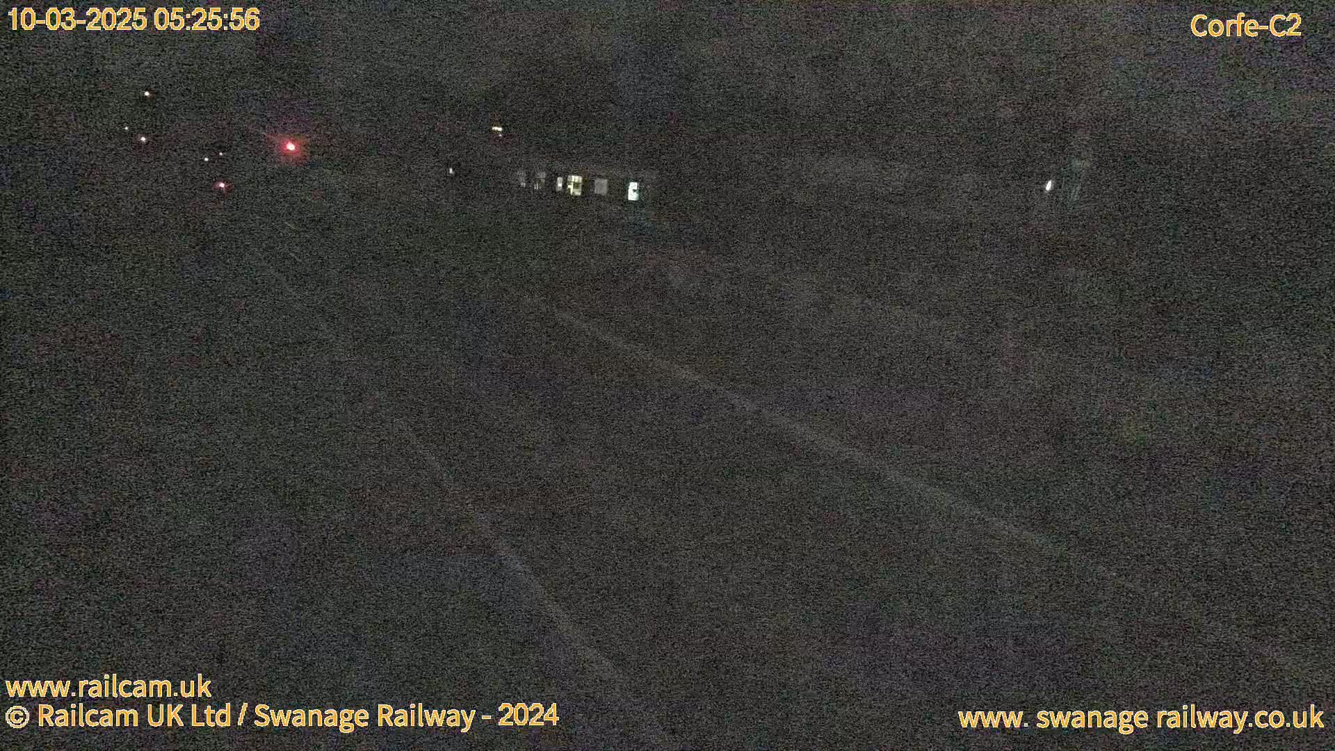 A dimly lit nighttime scene shows a train traveling on a railway track.
