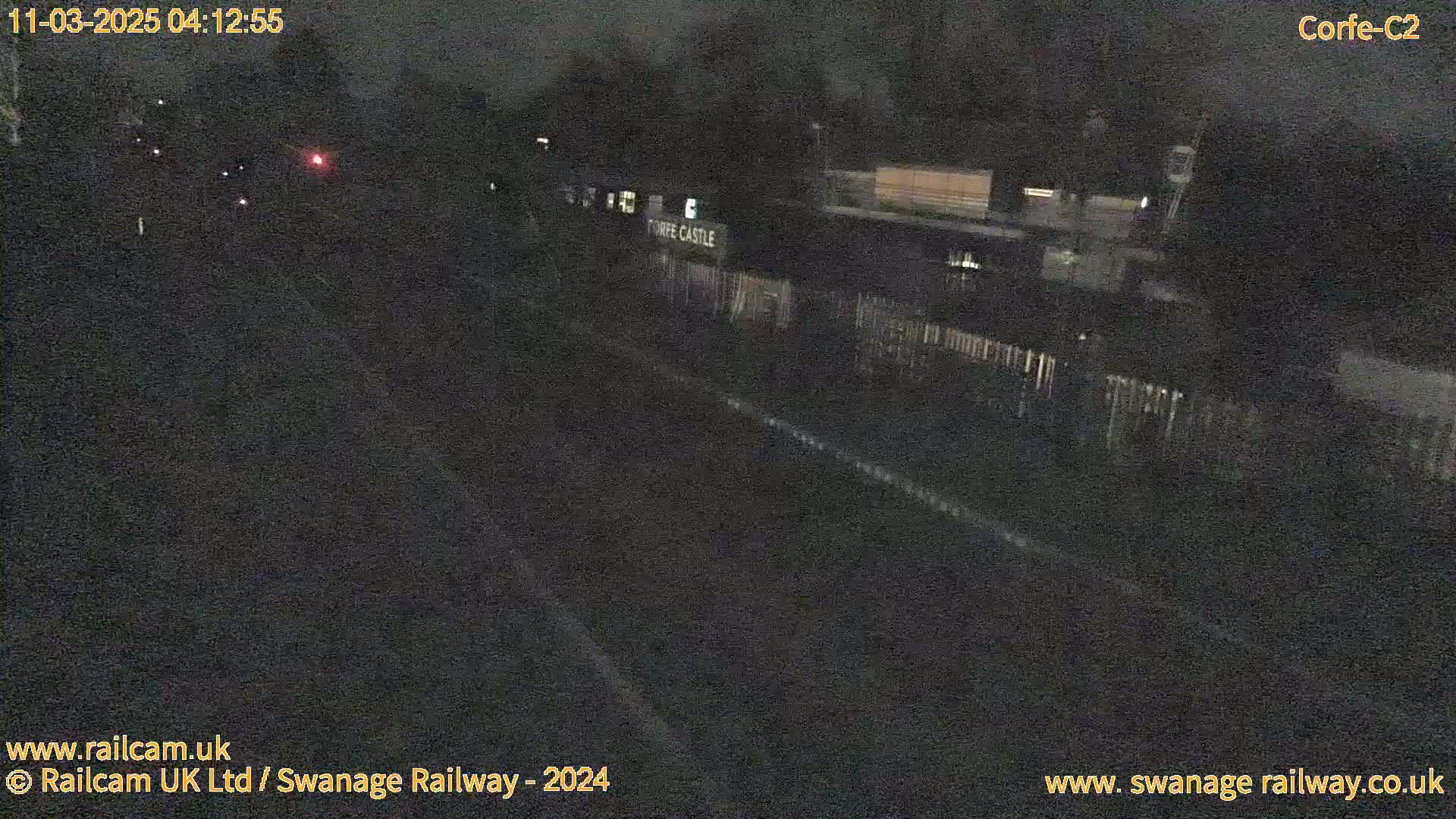 A nighttime, low-light view of a railway station with a few distant lights visible.