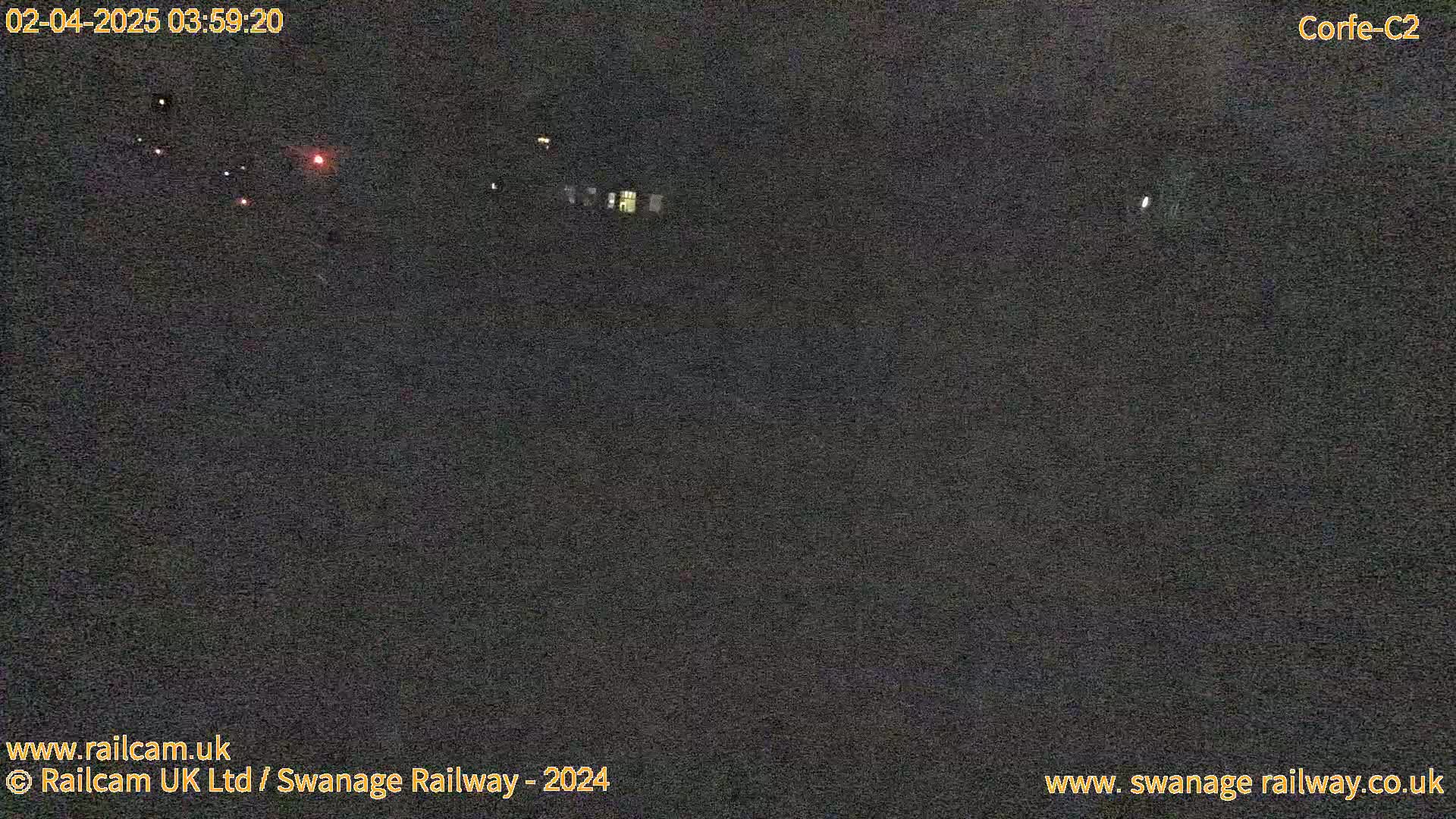 A dark, nighttime scene shows a few distant lights in the distance.