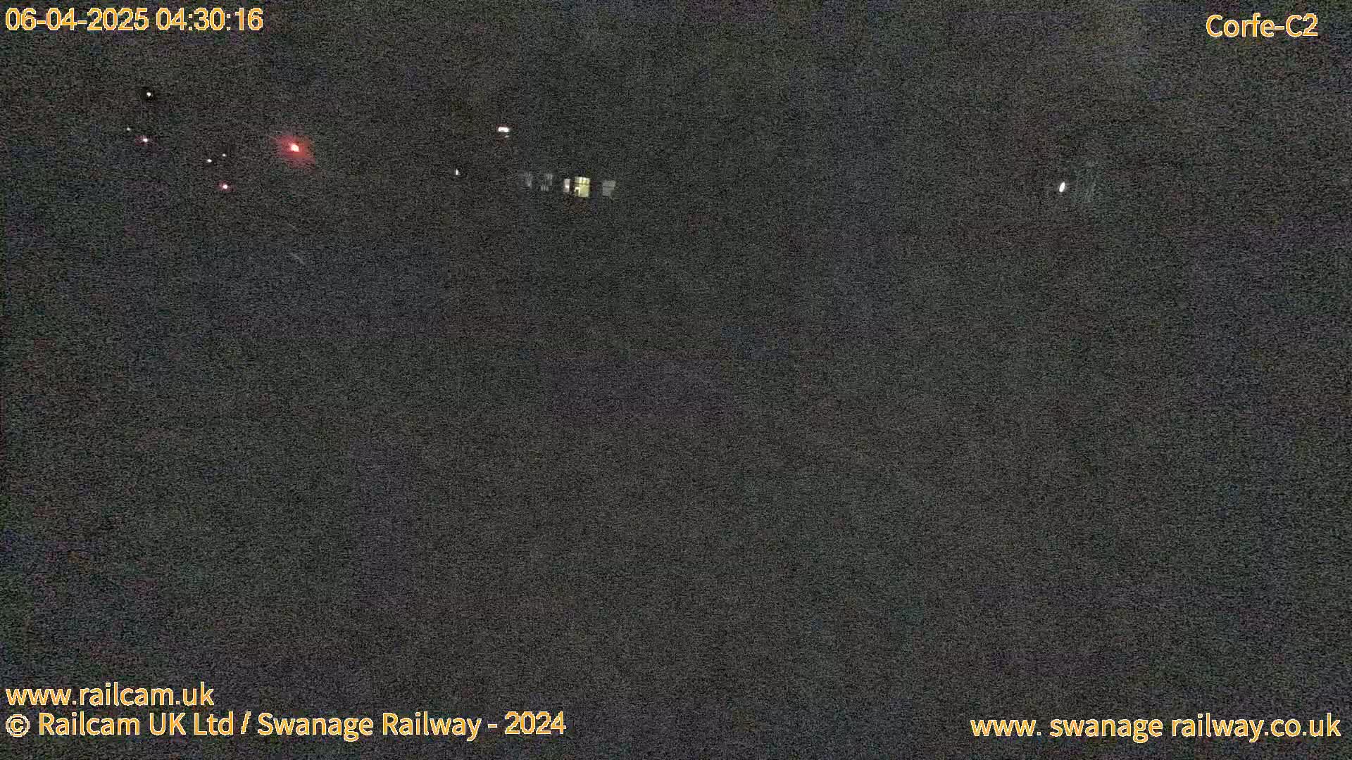 A dark, nighttime scene shows faint lights in the distance.