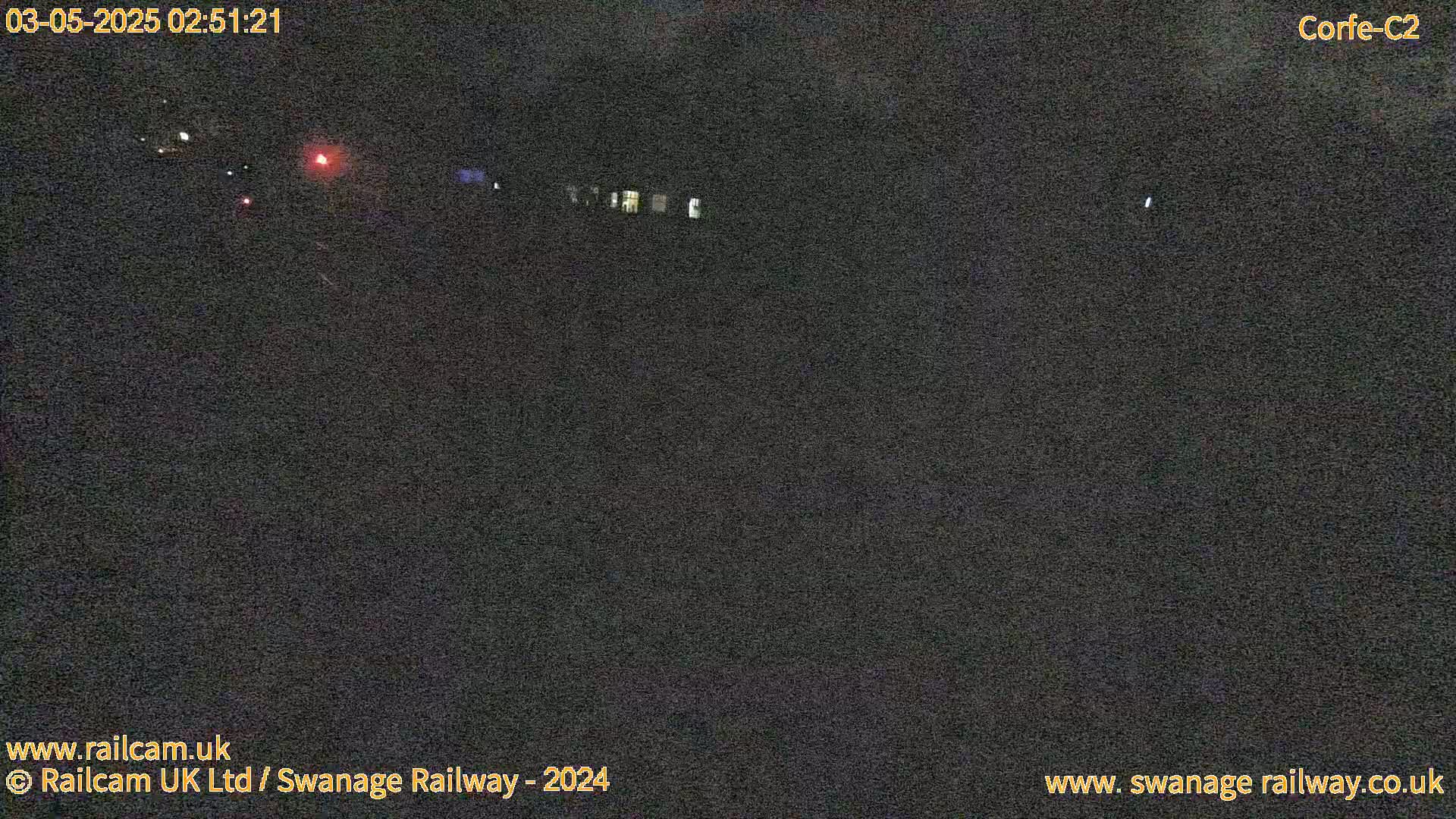 A nighttime, low-light outdoor scene shows a dark area with faint lights in the distance.