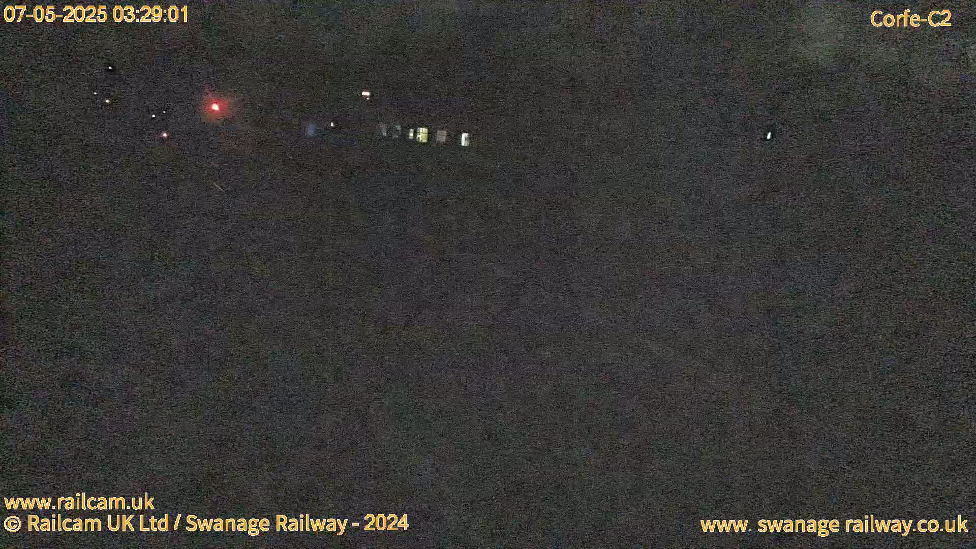 A nighttime, low-light view of a dark area with a few distant, faint lights.