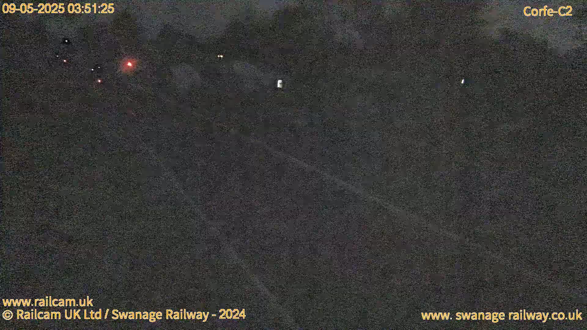 A dark, nighttime view of a roadway shows a few distant, faint lights.