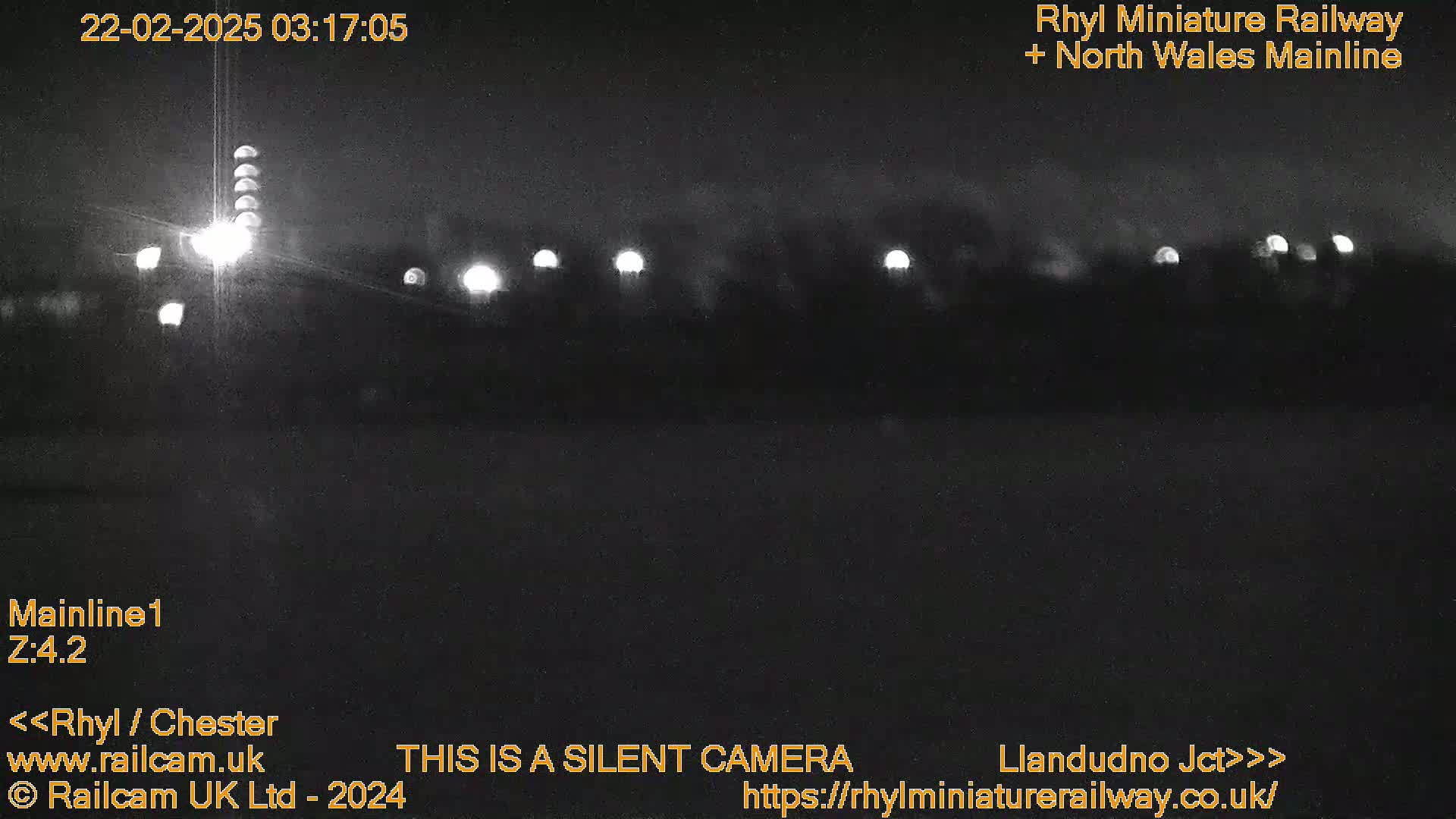A nighttime, low-light view of a dark landscape with several distant lights.