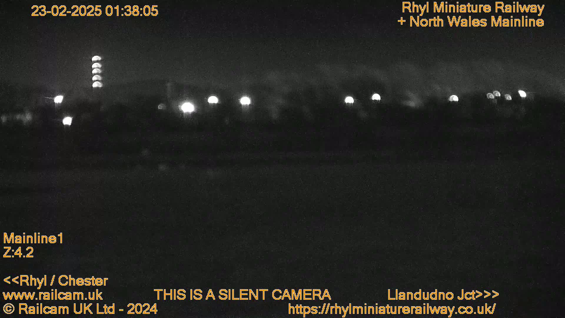 A nighttime, low-light view of a dark landscape with several distant lights.