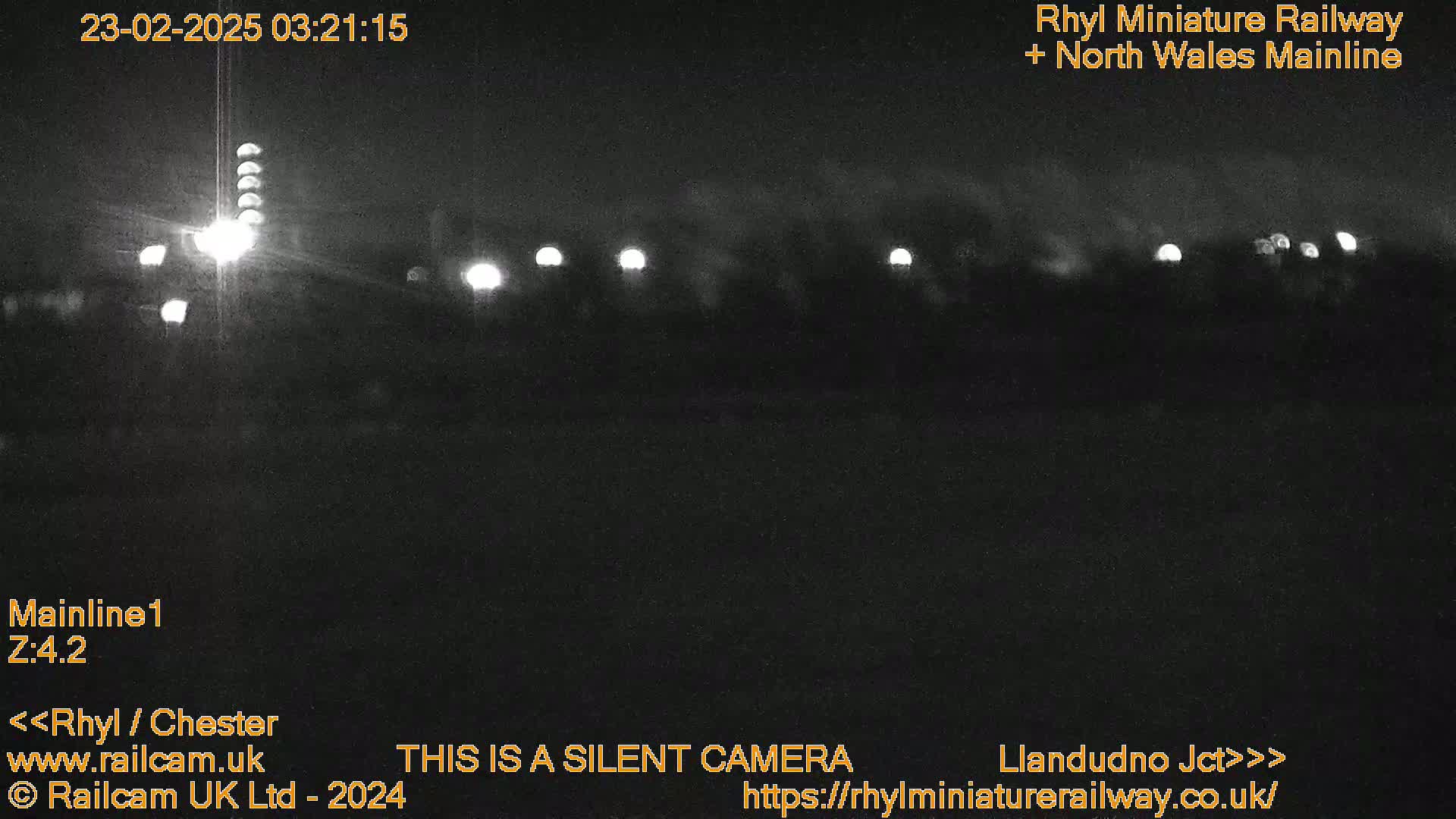 A nighttime, low-light view of a railway line with several distant lights visible.