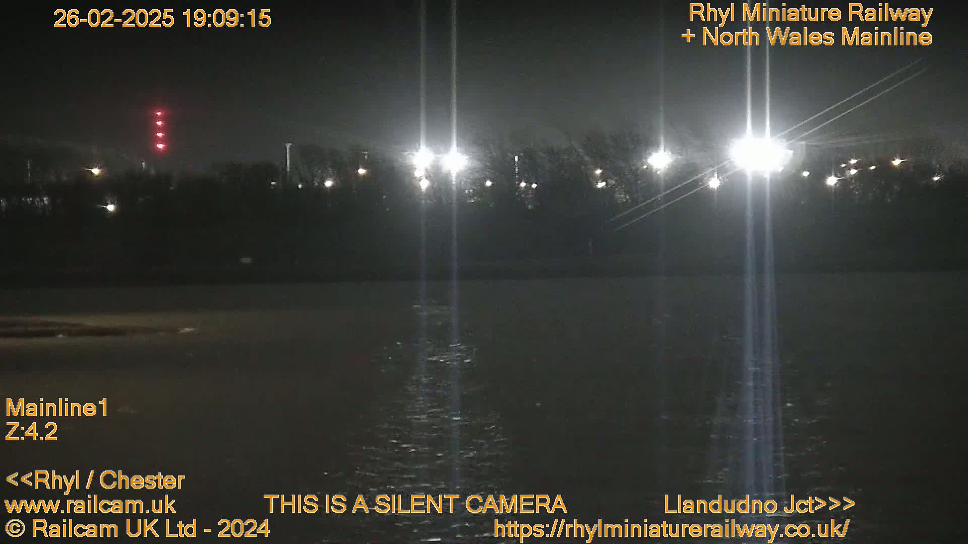 A nighttime view of a dark body of water under a dark sky illuminated by several bright lights across the far bank.