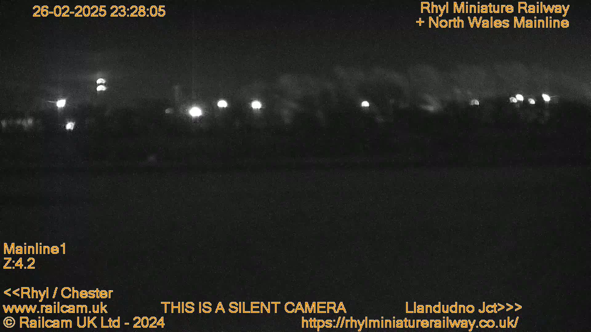 A nighttime, low-light view of a railway line with faintly visible lights in the distance.