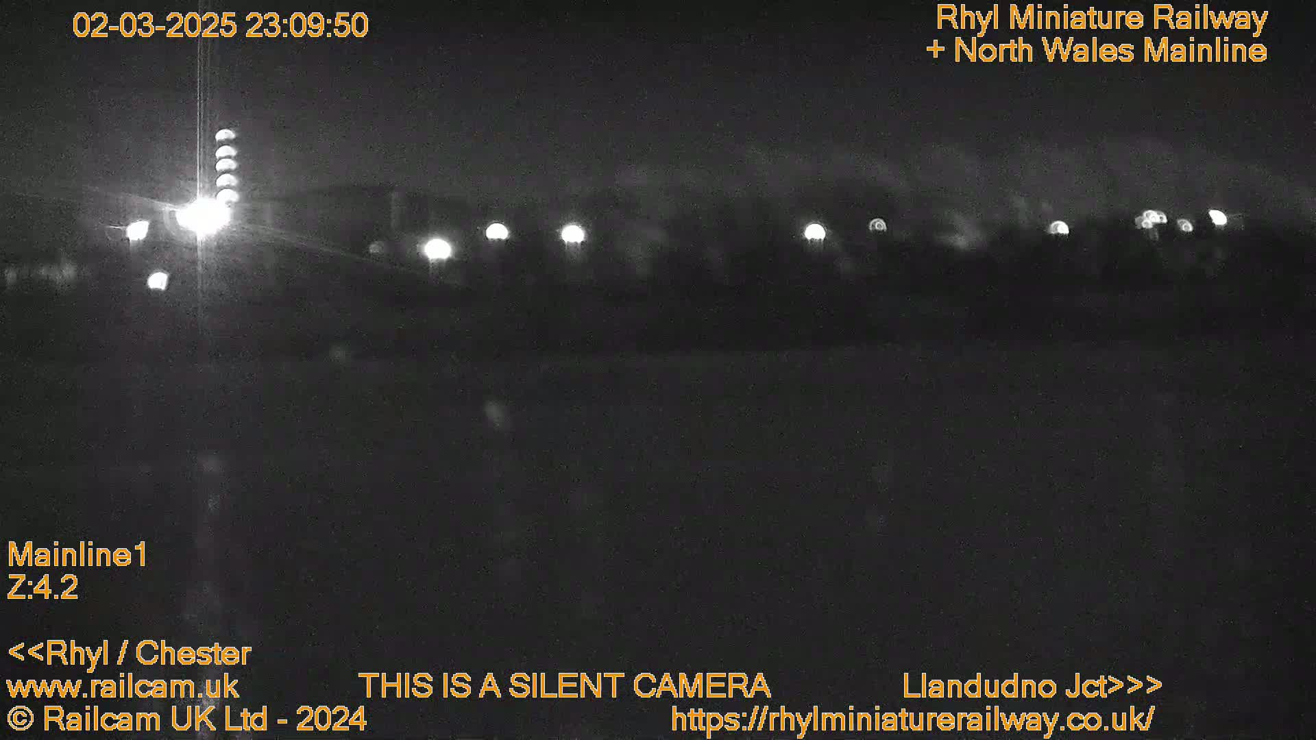 A nighttime, low-light view of a railway line with several distant lights visible.