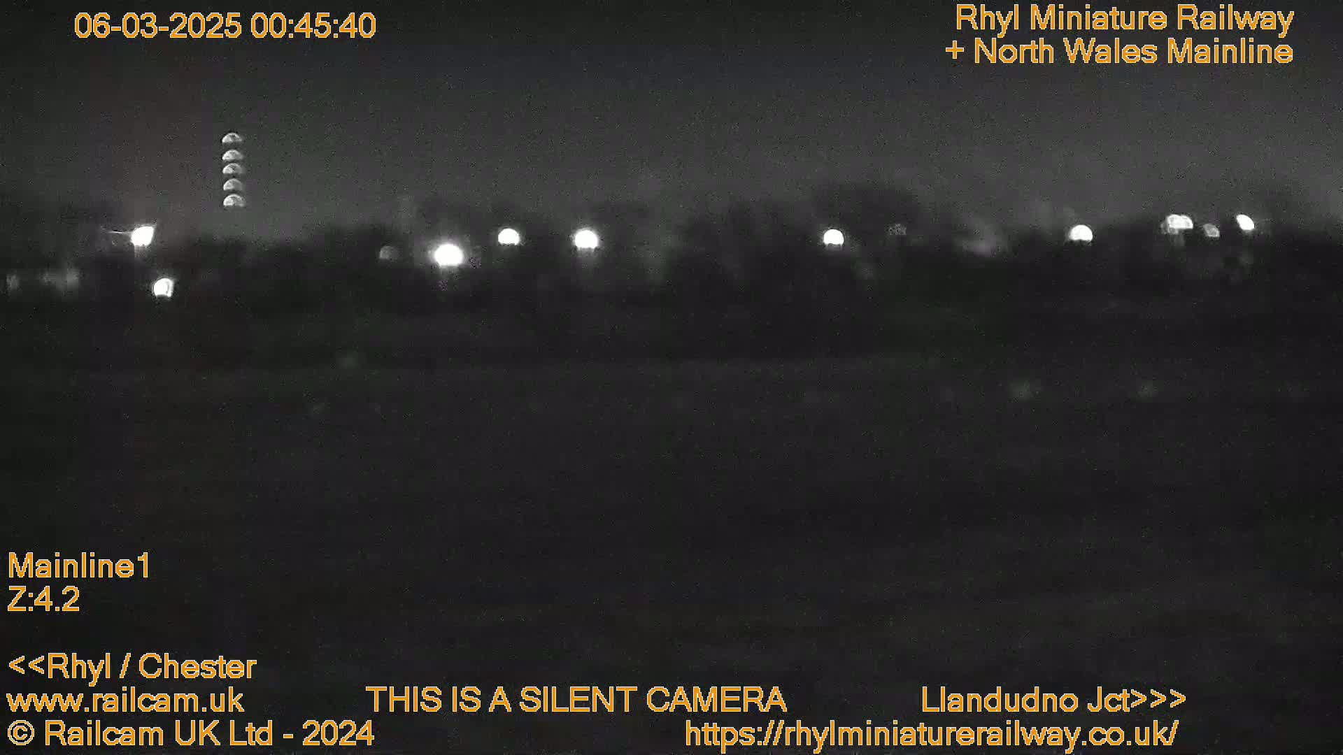A nighttime, low-light view of a dark landscape with a few distant lights.
