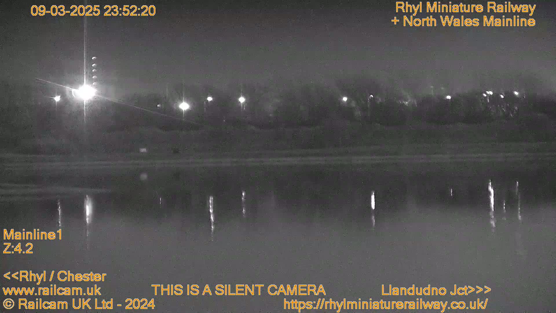 A nighttime, low-light view of a calm body of water reflecting lights from across the shore.