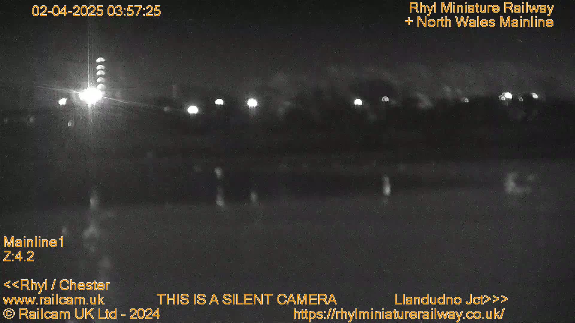 A nighttime, low-light view of a dark landscape with several distant lights.