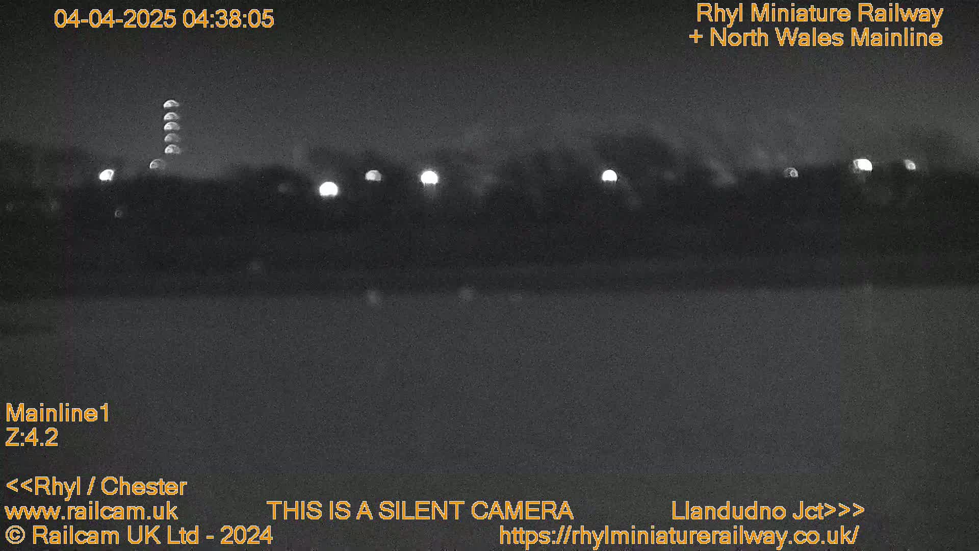 A nighttime, low-light view of a dark landscape with a few distant lights.