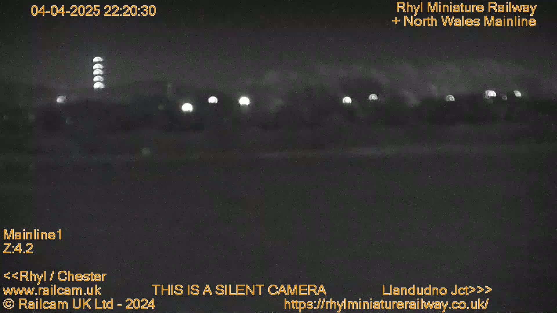 A nighttime, low-light view of a dark landscape with several distant lights.