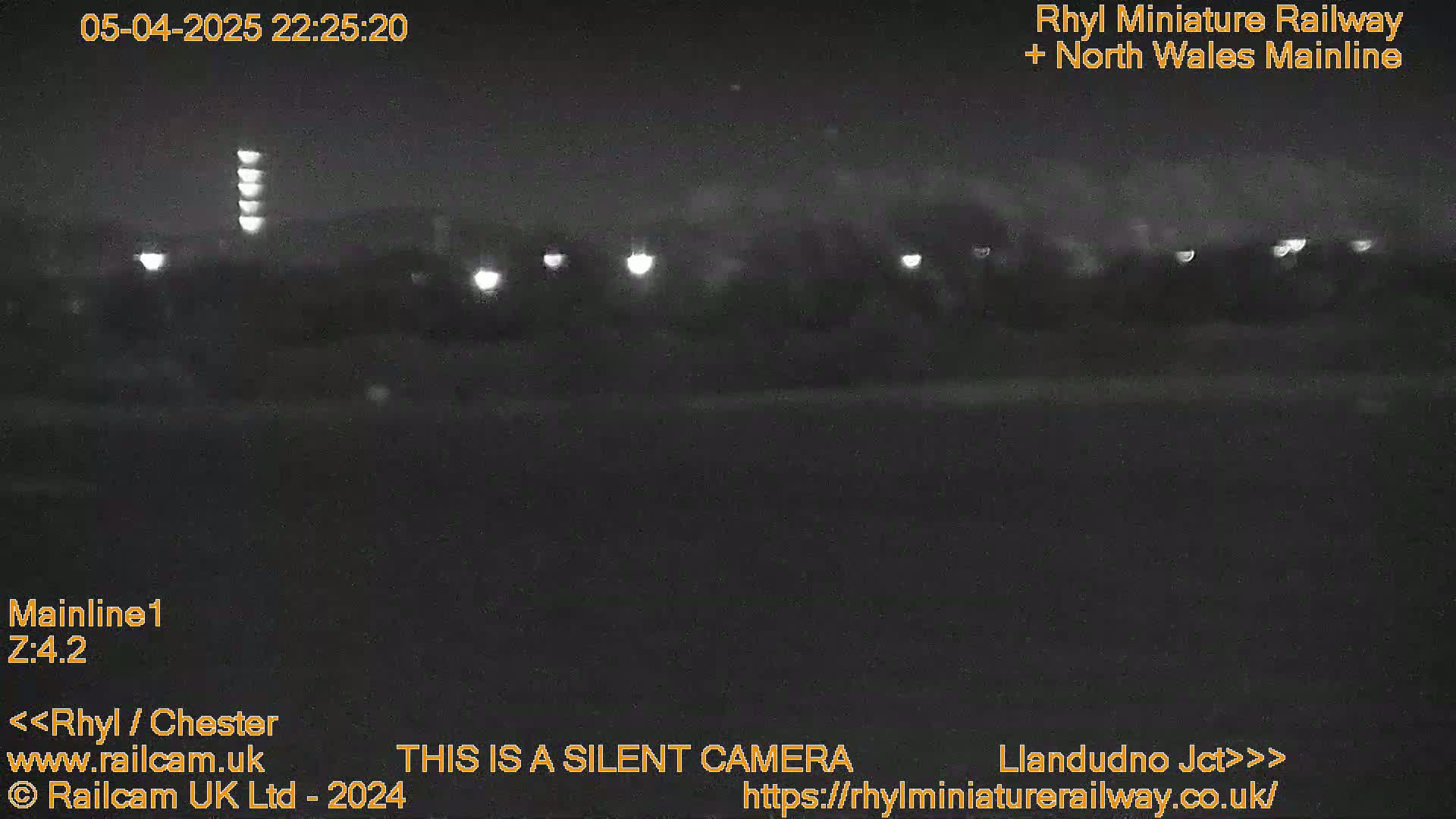 A nighttime, low-light view of a dark landscape with a few distant lights visible.