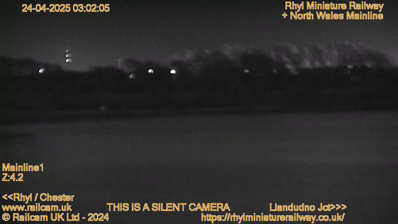 A nighttime, low-light view of a dark landscape with a few distant lights visible.