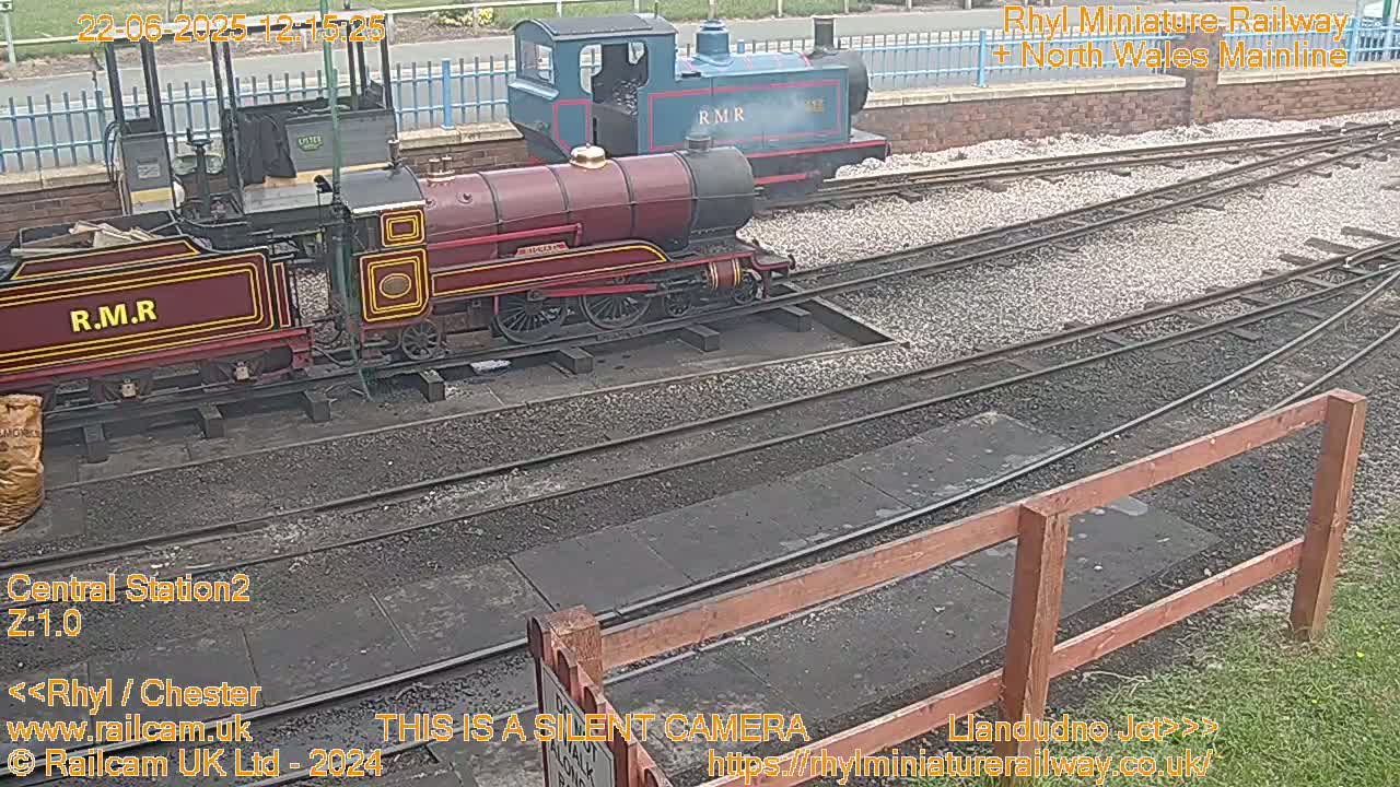 Two small locomotives are parked on a railway track in an outdoor area with overcast skies.