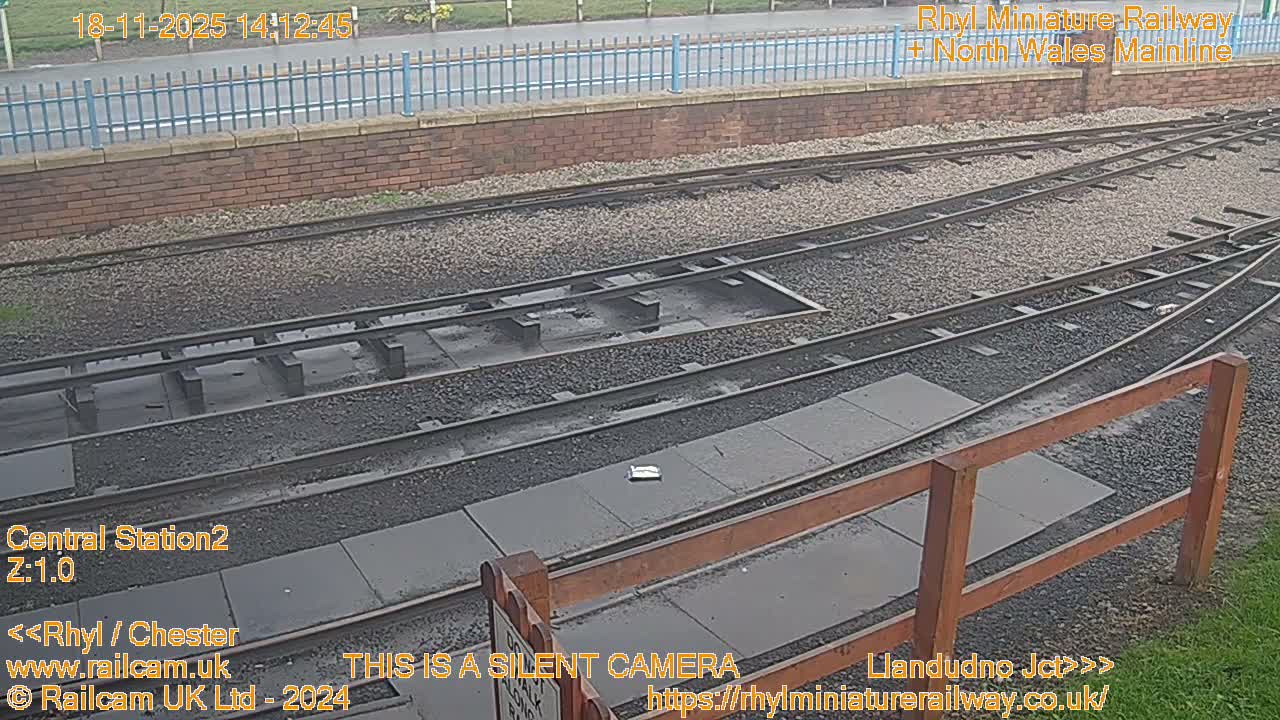 A wide expanse of water gleams intensely with the glare of a low sun under a bright, hazy sky, silhouetting a distant shore lined with bare trees.