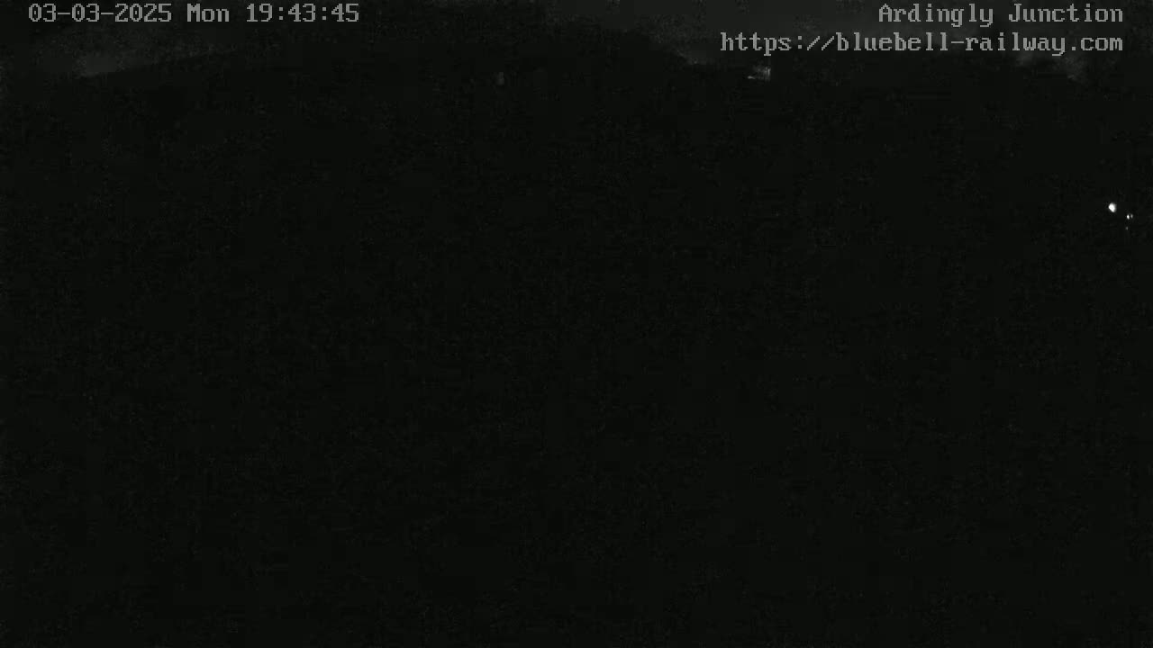 A nighttime, dark image shows a mostly black scene with faint, distant lights.