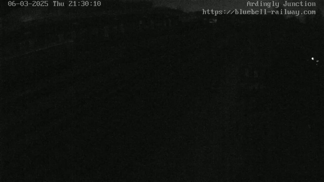 A dark, nighttime image shows a mostly black scene with indistinct shapes in the far distance.