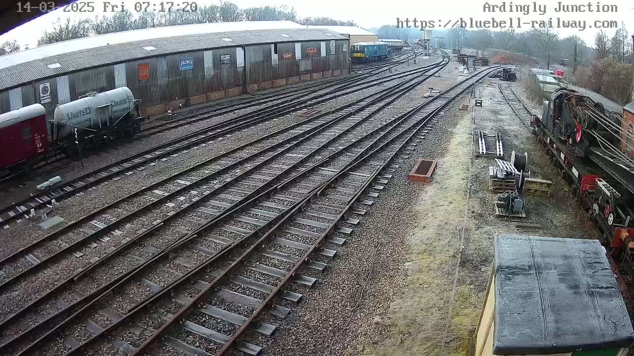 A high-angle view of a railway yard with multiple train cars and tracks, under an overcast sky.