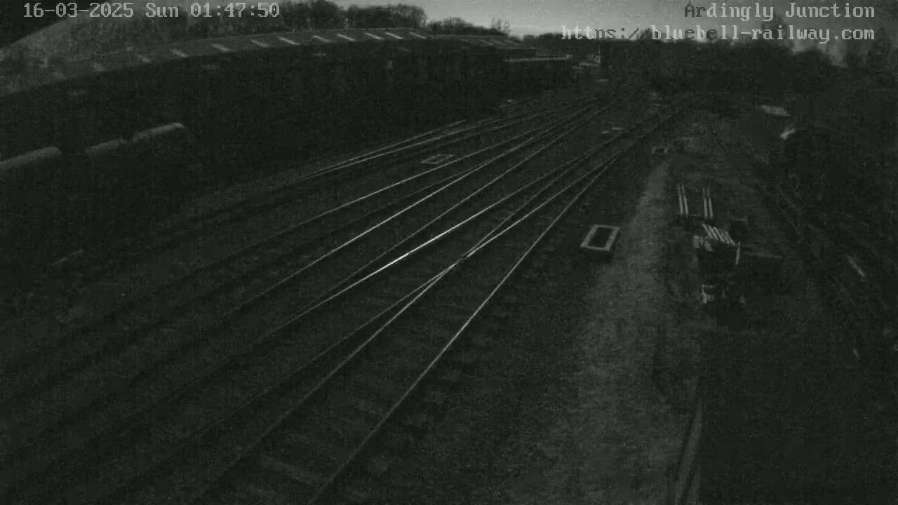 A high-angle, nighttime view of a railway junction with several sets of tracks converging.