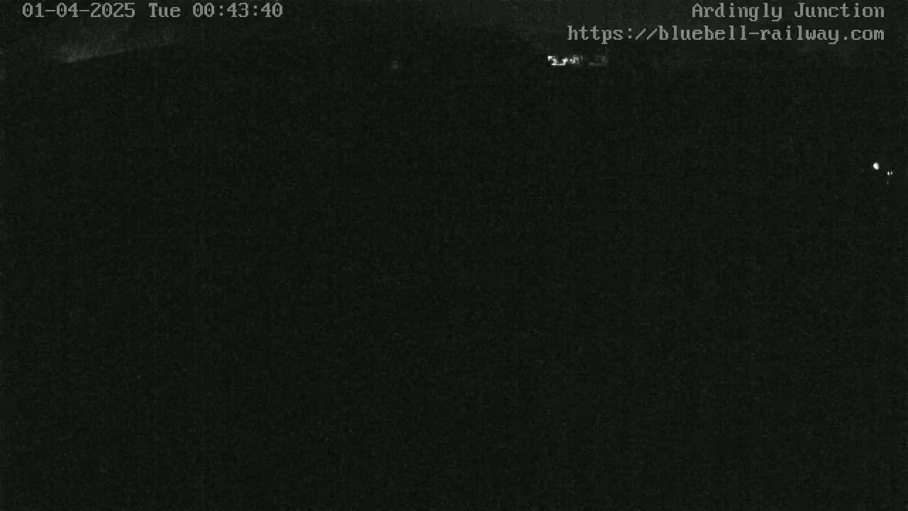 A nighttime, dark image shows a mostly black, blurry view of an outdoor scene.