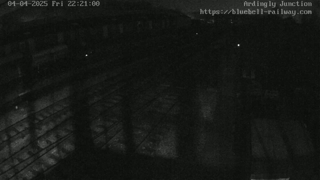 A nighttime, low-light view of train tracks and a railway structure.