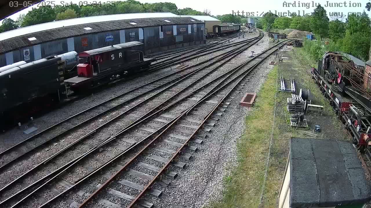 Several railway cars and locomotives are parked on a railway yard on a sunny day.