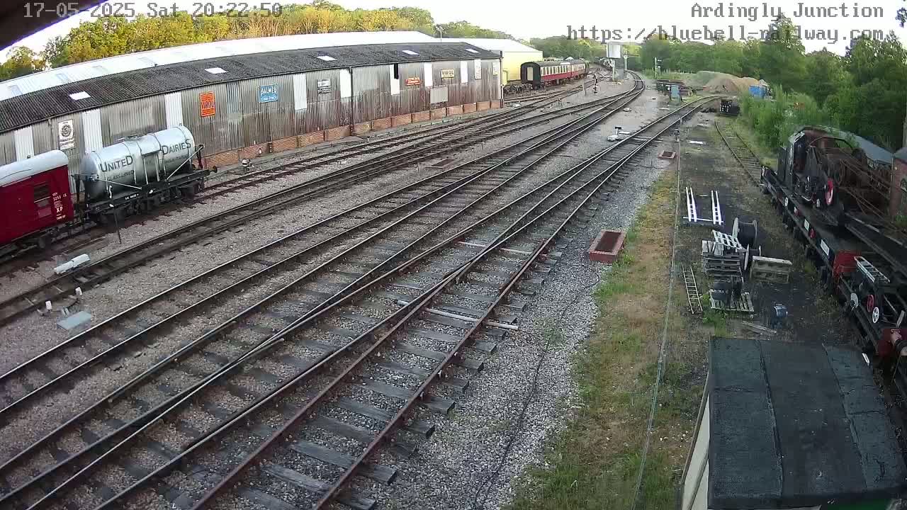 A railway yard with multiple train cars and tracks, under a partly cloudy sky.