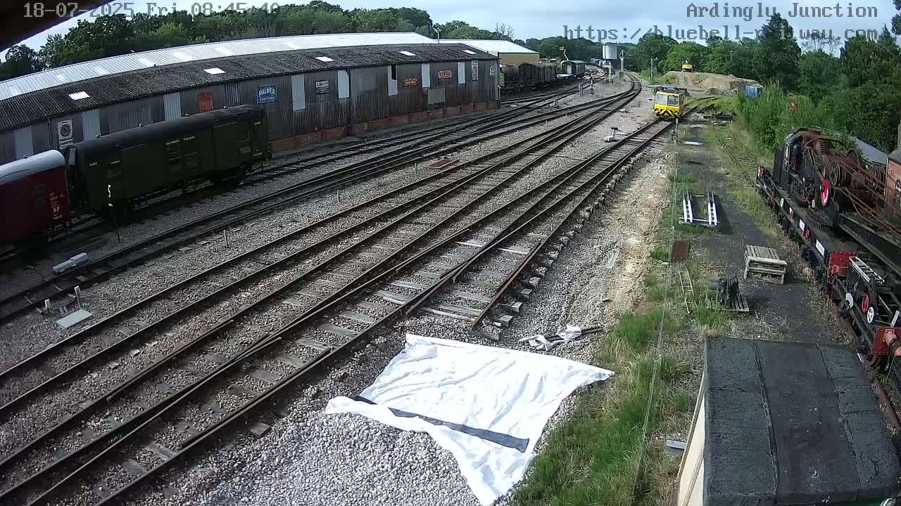 A railway yard with multiple train cars and tracks under partly cloudy skies.